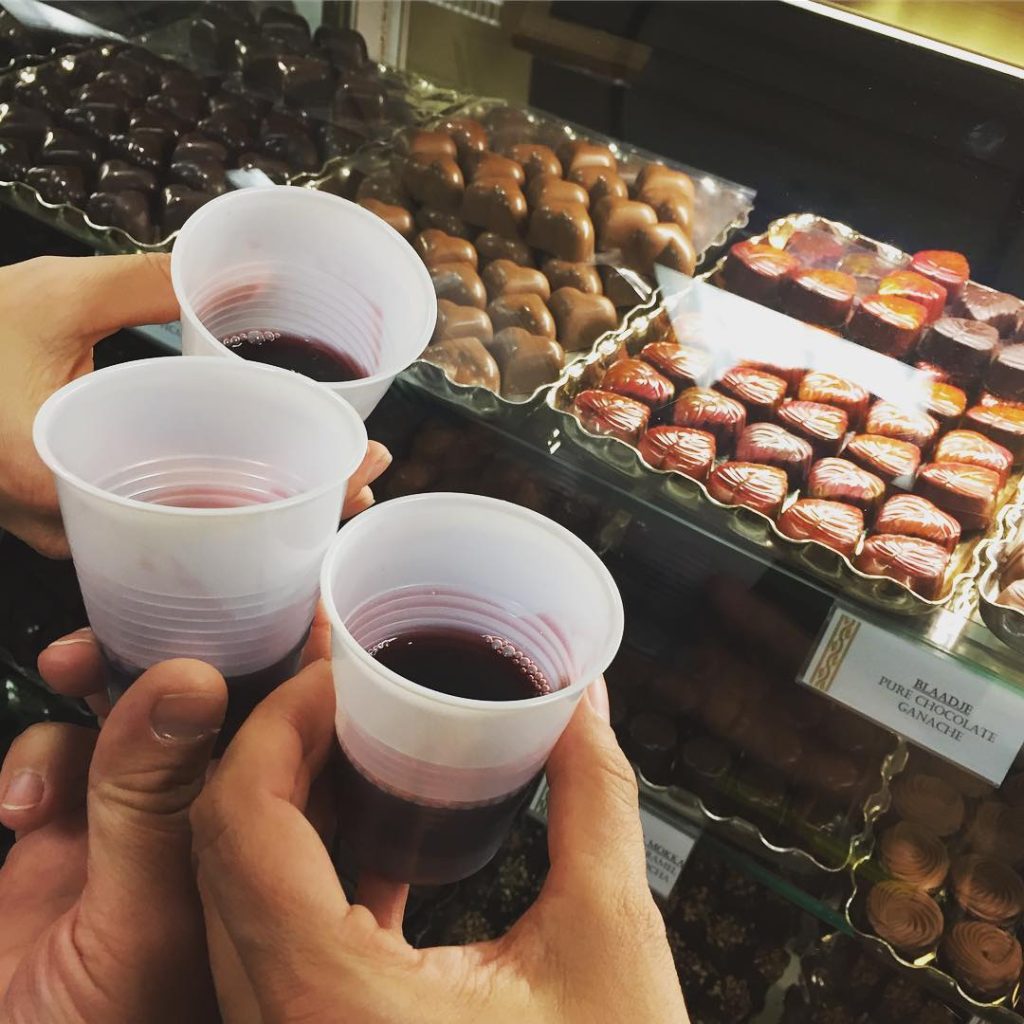 3 glasses of wine in front of a case of chocolates the night of the Evanston Charity Wine Walk